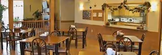 Empty dining room with tables, chairs, a serving counter, and garland.