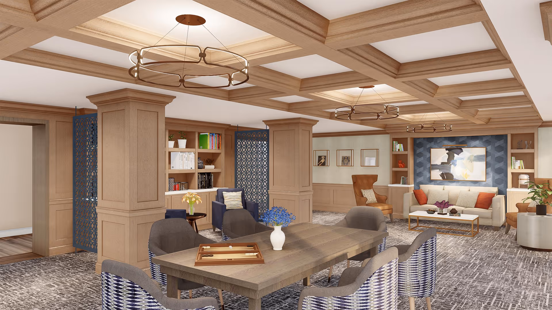 Spacious communal living room with a central wooden table, upholstered chairs and sofas beneath a coffered ceiling.