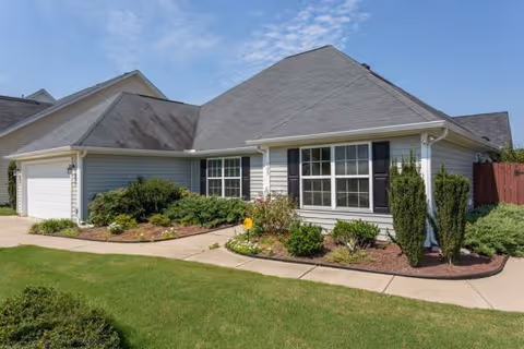 Single-story assisted living facility front exterior with manicured landscaping and a sidewalk.
