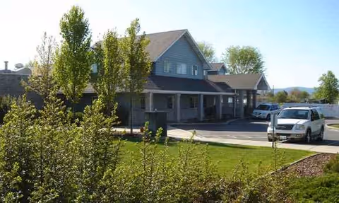Exterior view of Brighton Court Assisted Living facility with parked cars and landscaping.