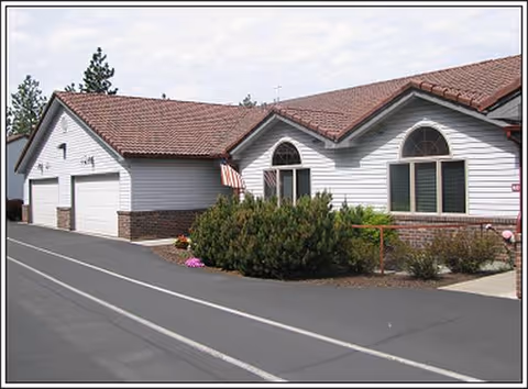 Front view of a single-story senior living facility with garages and landscaped entrance.