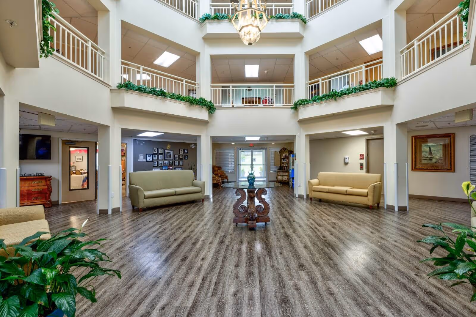 Spacious two-story atrium lobby with sofas, plants, a central decorative table, and upper balconies.