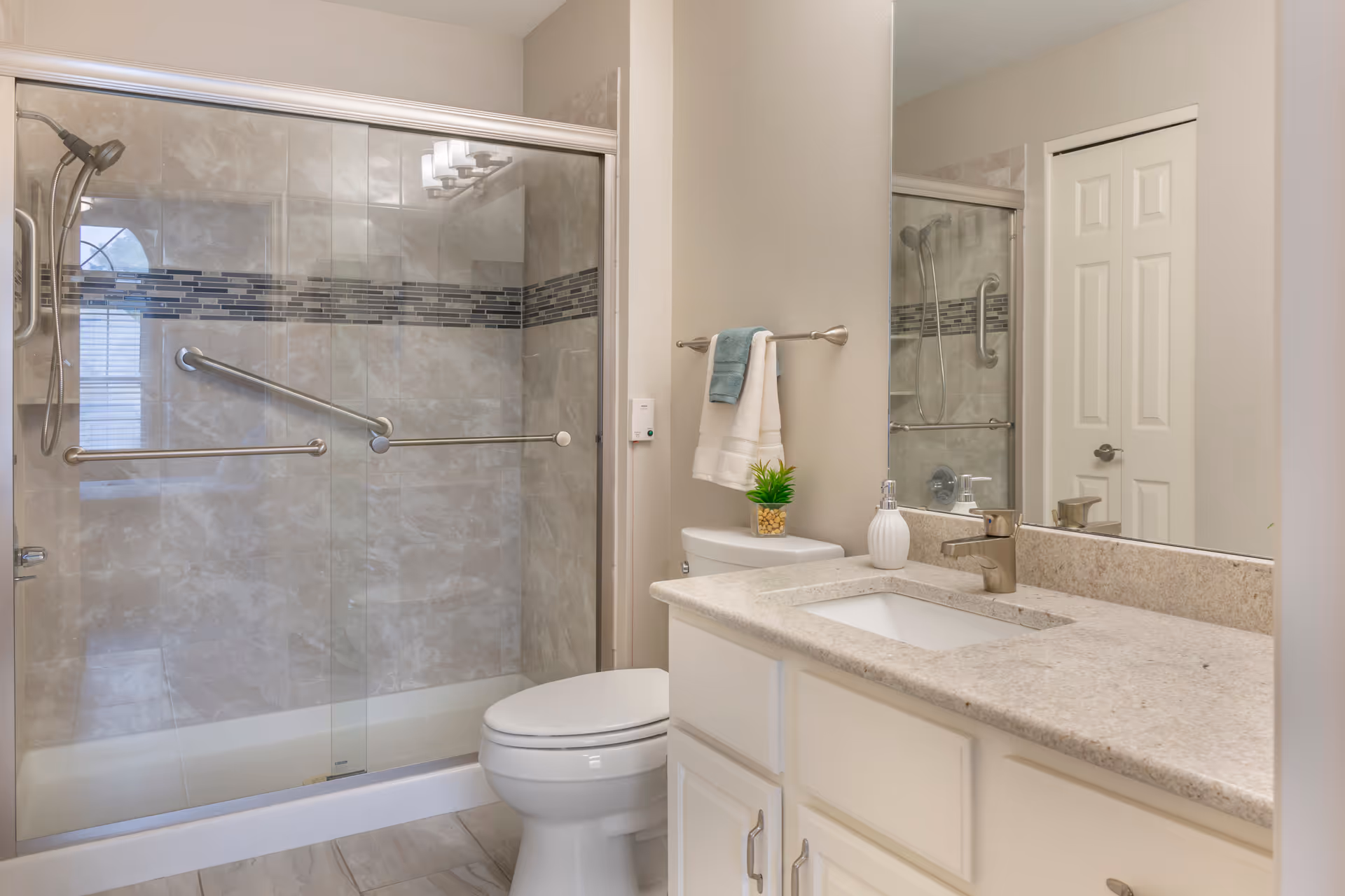 Clean, modern bathroom with a glass-enclosed shower, toilet, and a vanity with sink and mirror.