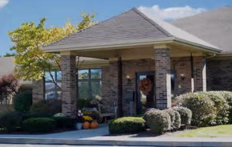 Entrance of a brick nursing center with a covered porch and trimmed shrubs.