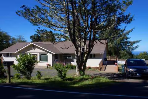 Graceland Care Homes front exterior with a tree, lawn, and a parked car.
