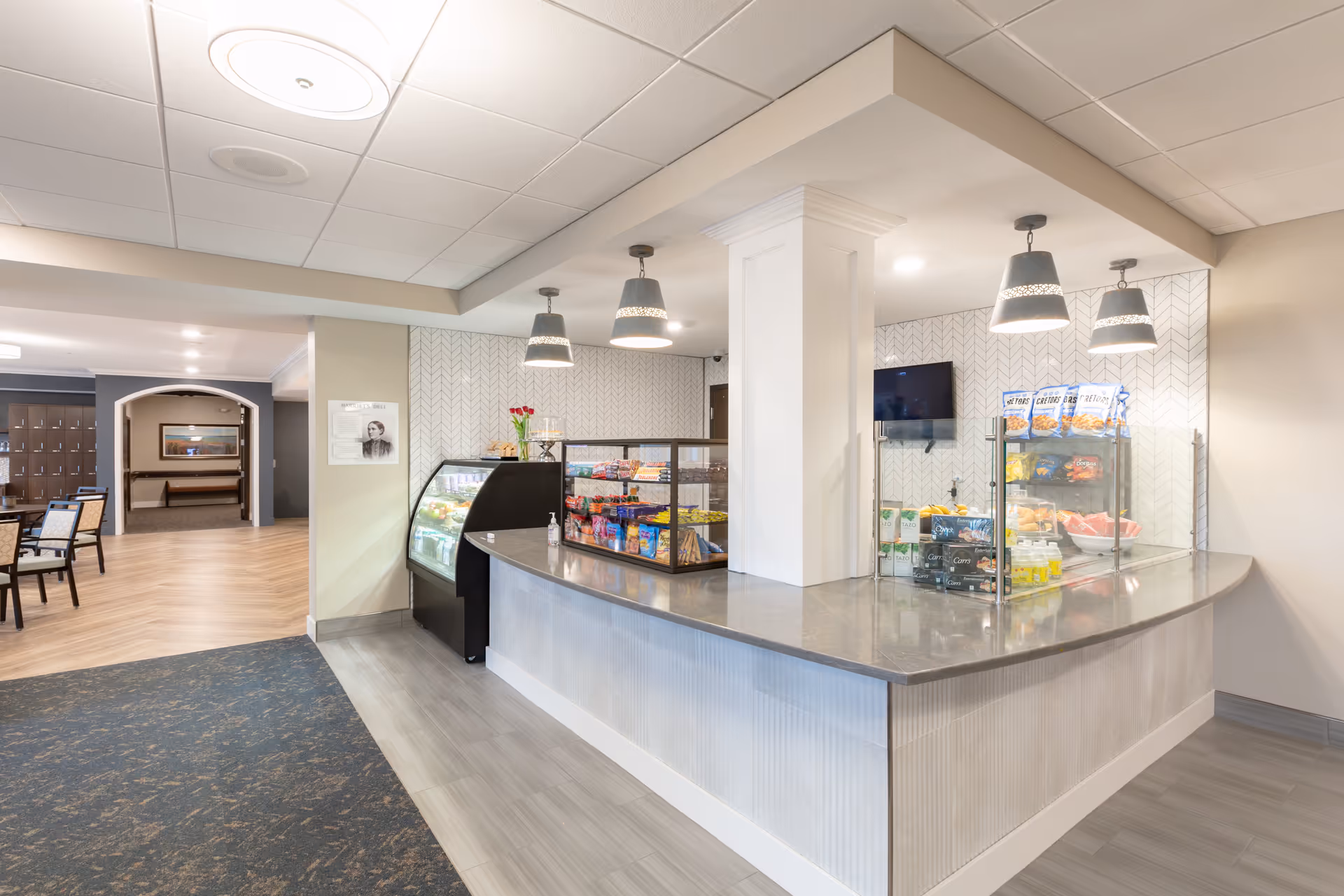 Well-lit indoor snack bar and service counter with glass displays, pendant lights, and seating visible in the background.