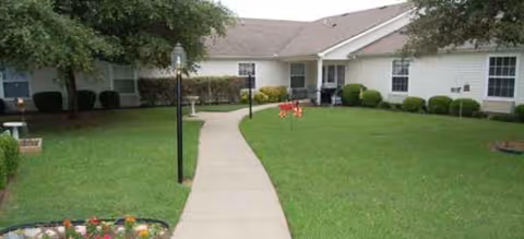 Front view of Brookdale Corsicana facility with a curved sidewalk, manicured lawn, and entrance.