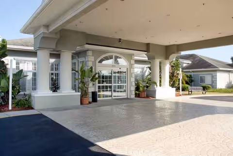 Exterior view of Life Care Center entrance with columns, glass doors, and potted plants.