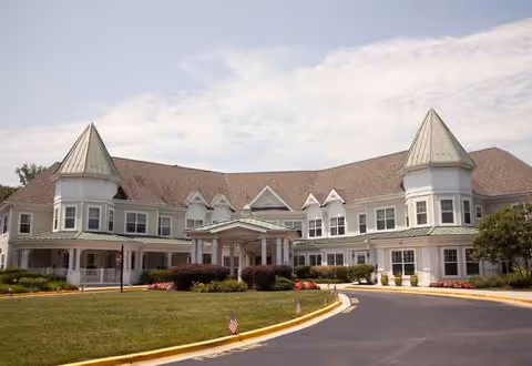 Exterior view of a Sunrise senior living facility with peaked towers and a curved entrance.