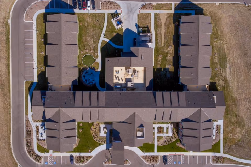 Aerial view of The Healthcare Resort Of Topeka showing a large building complex with multiple wings, surrounded by parking lots, pathways, and landscaped green areas.