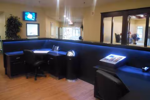 Interior reception area with a curved blue seating counter and desks in a senior living facility.