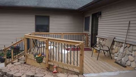 Patio deck with chairs and railing outside a senior living facility.