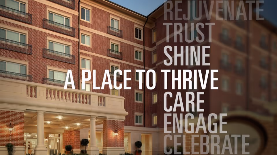 Front entrance of a multi-story brick senior living building with large overlaid promotional text reading "A PLACE TO THRIVE".