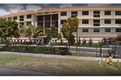 Exterior view of a multi-story senior living facility named St Joseph's Residence with large windows, trees, and a fenced area in front under a partly cloudy sky.