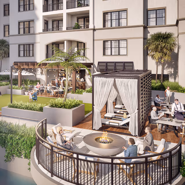 Outdoor courtyard of a senior living community with a circular fire pit, seating, a draped cabana, dining tables, and people socializing in front of a multi-story building.