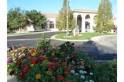 Front view of San Marino Retirement Community-Assisted Living with blooming flowers and curved driveway.