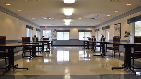 A spacious, well-lit communal dining area with empty tables and chairs along the walls.