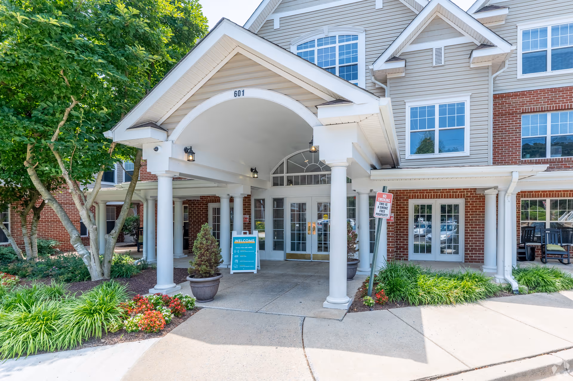 Front entrance of Manor at Colesville, a brick building with white columns and glass doors.