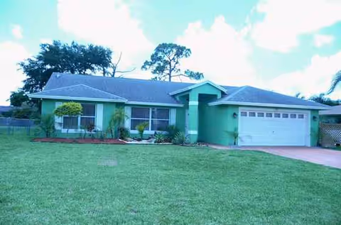 Green, single-story building with attached garage and a well-kept front yard.