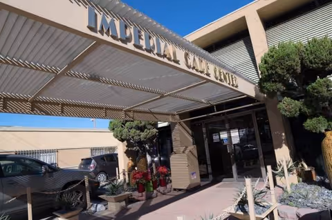 Front entrance of Imperial Care Center with glass doors, awning, and potted plants.