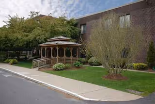 Exterior view of CareOne at Northampton with brick building, gazebo, and landscaped front yard.