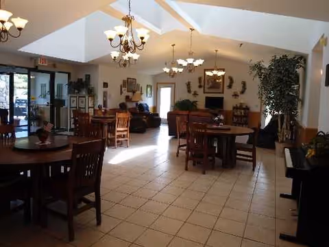 Spacious senior living dining area with round tables, chairs, and chandeliers.