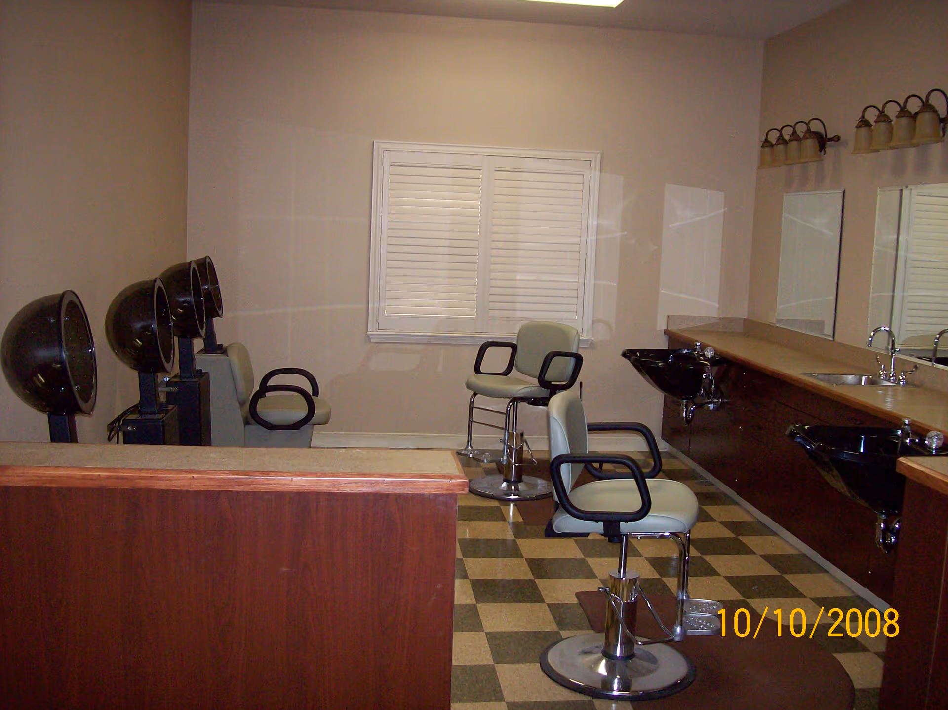 Small salon area with styling chairs, hooded hair dryers, wash sinks, mirrors, and a counter inside the facility.