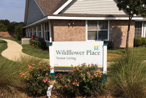 Exterior view of Wildflower Place Senior Living with a landscaped front sign.