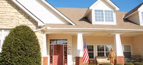 Front exterior of Brookdale Norman with porch, flag, and resident near entrance.