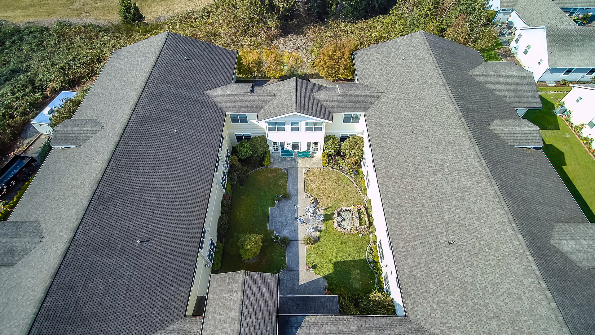 Aerial view of a U-shaped assisted living building surrounding a landscaped central courtyard with walkways, seating and a small fountain.