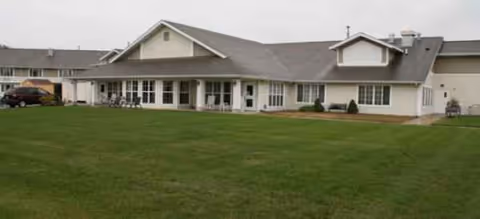 Front view of a single-story senior living building with a green lawn.