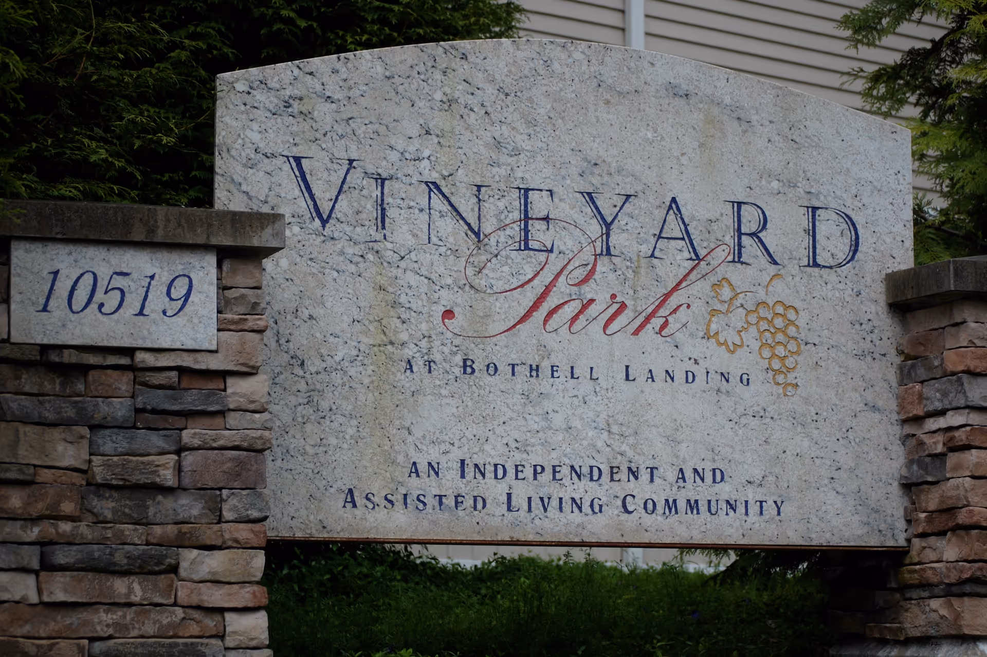 Stone entrance sign reading "Vineyard Park at Bothell Landing" with an address plaque "10519" and a grape motif.