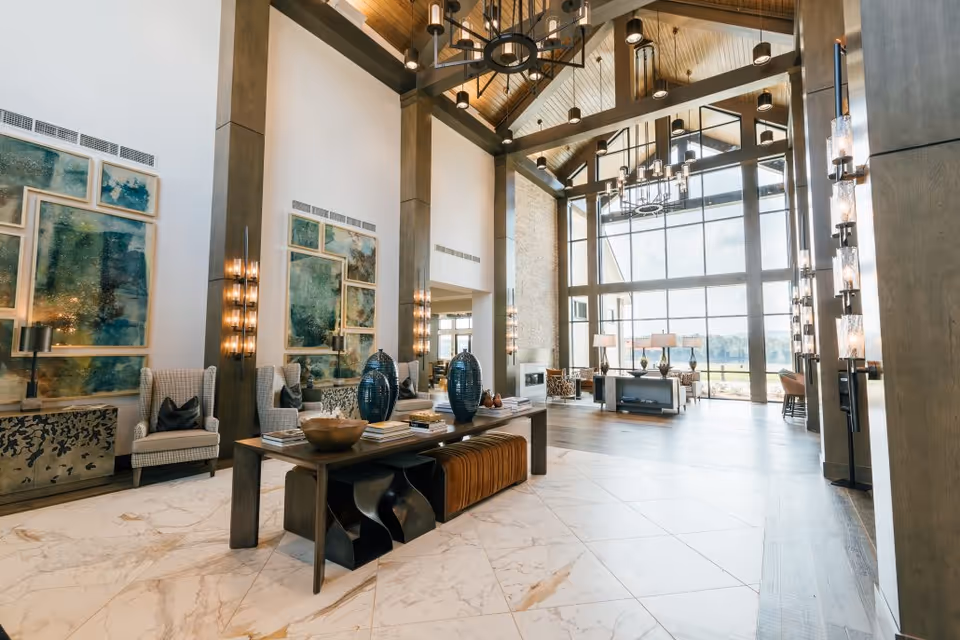 Bright, high-ceilinged lobby with floor-to-ceiling windows, seating areas, decorative art, and contemporary lighting.