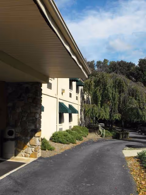 Exterior view of Newark Manor Nursing Home with driveway, shrubs, and trees.