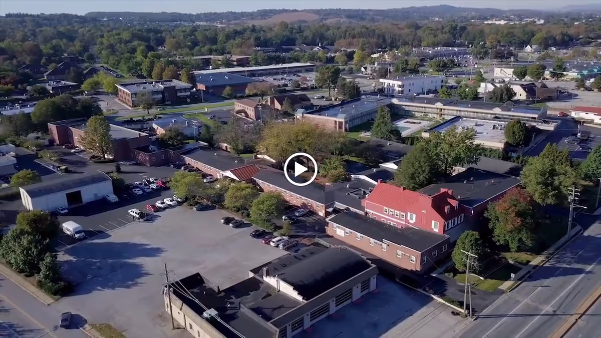 Aerial view of a senior living facility named Oak Leaf Manor South, showing multiple connected buildings with parking lots, surrounded by trees and nearby roads in a suburban area.