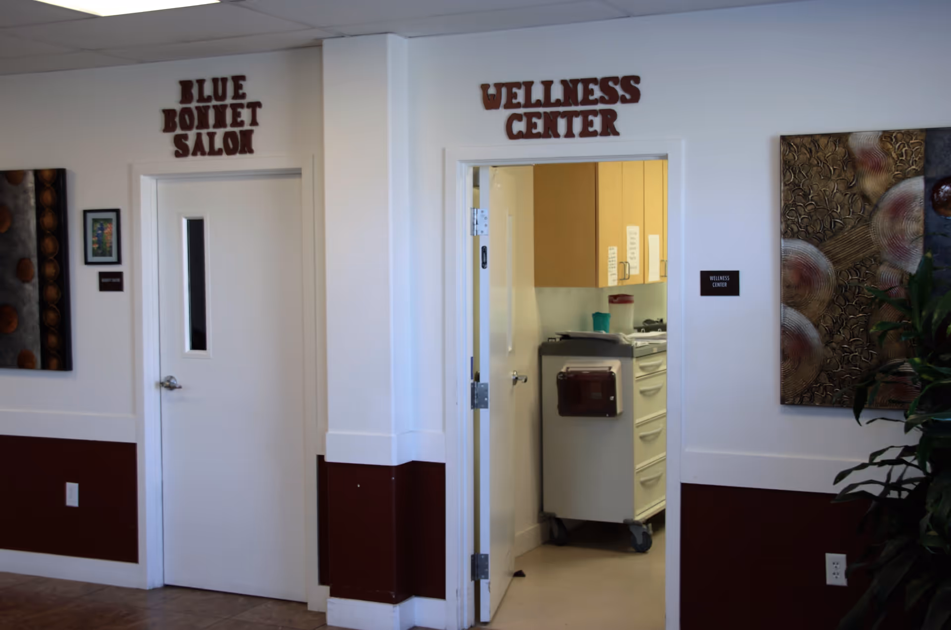 Interior hallway showing doors labeled "Blue Bonnet Salon" and "Wellness Center," the latter open to a room with a medical cart.