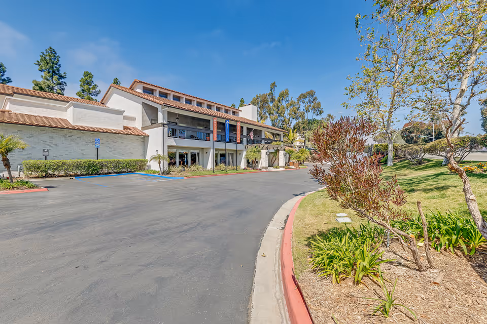 Exterior view of Encinitas Senior Living building with parking and landscaped grounds.