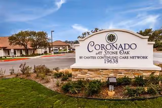Exterior view of the Coronado at Stone Oak facility sign with surrounding landscaping.