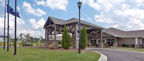 Exterior view of PruittHealth Blythewood entrance with porte-cochere, flagpoles, and landscaped lawn.