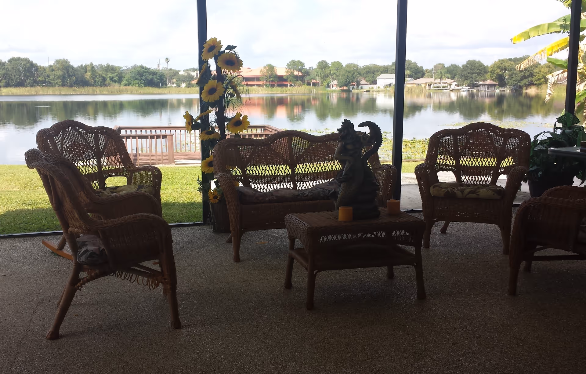 Lakeside screened patio with wicker chairs and a coffee table facing a calm lake.