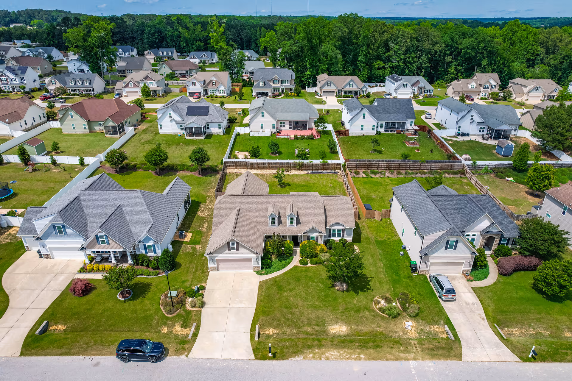 Aerial view of suburban single-family homes with lawns and driveways in a neighborhood.