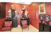 Salon-style room with two styling chairs, mirrors, sinks and hooded hair dryers against red patterned wallpaper.