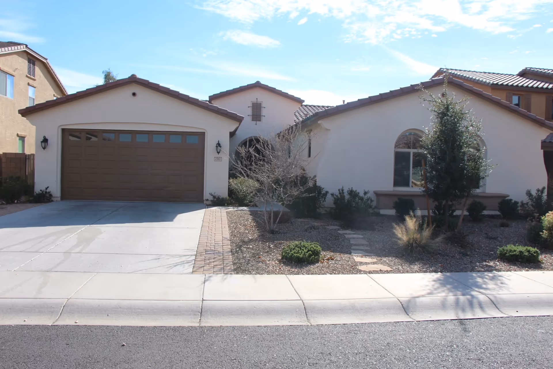 Front view of a single-story beige house-style building with a brown garage door.