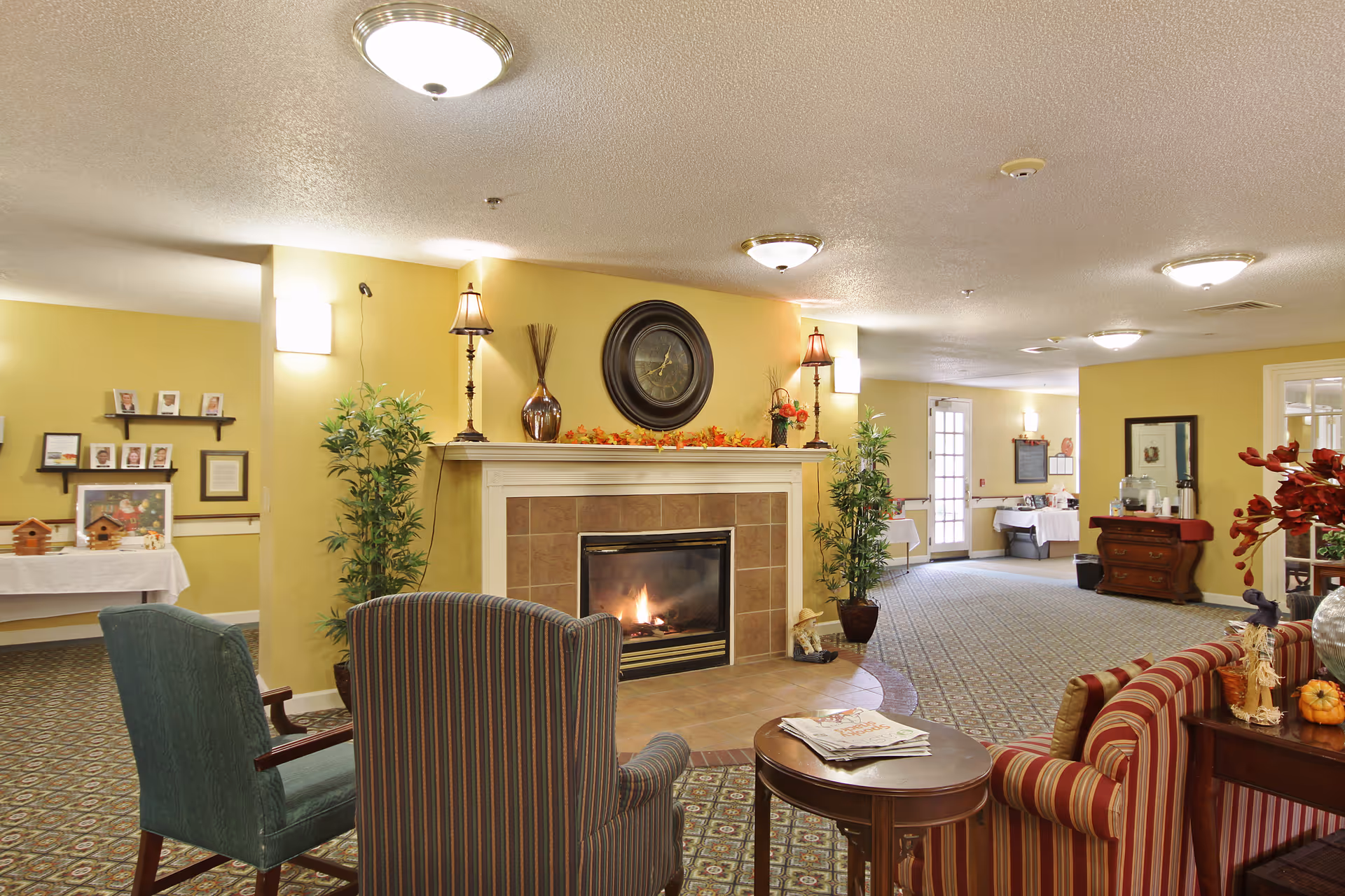 Cozy furnished common room with a lit fireplace, seating, and decorative accents.