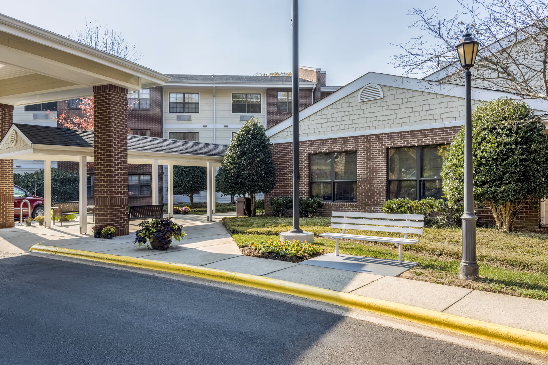 Exterior view of Solista Charlotte with brick building, benches, trees, and sidewalk.