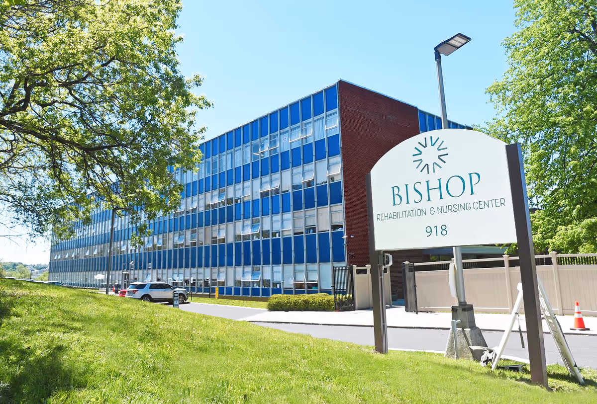 Exterior view of the Bishop Rehabilitation & Nursing Center building with its entrance sign and a grassy foreground.