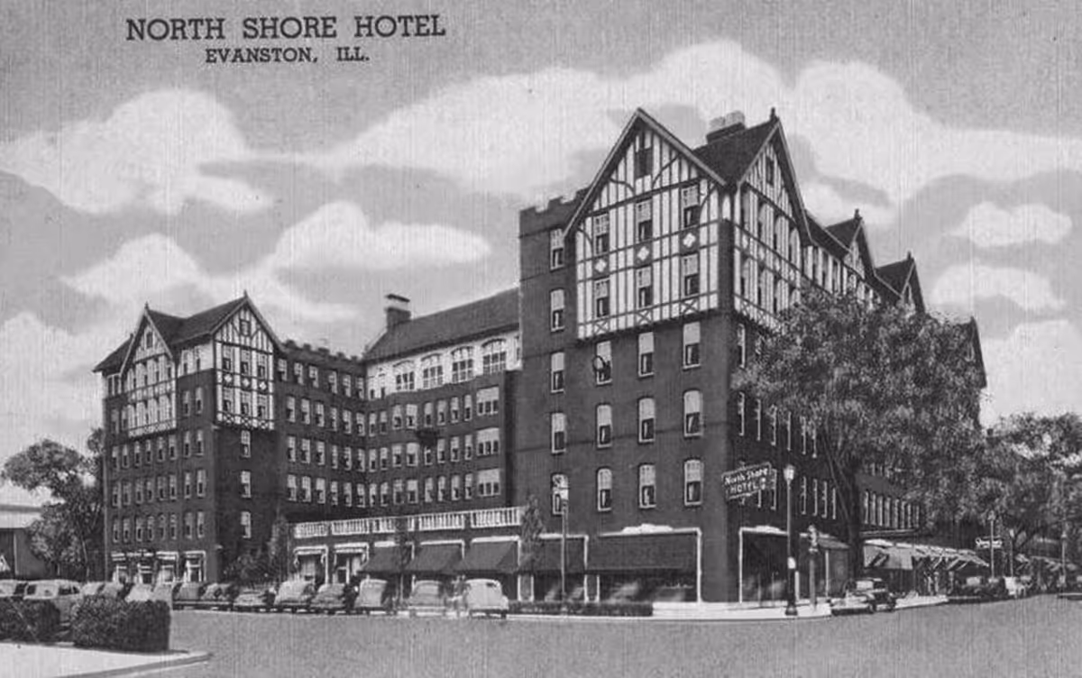 Black and white image of the North Shore Hotel in Evanston, Illinois, showing a large multi-story building with Tudor-style architectural elements and several parked cars along the street.