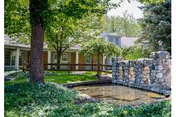 Stonebridge Manor outdoor area with a stone water feature, trees, and a building facade.