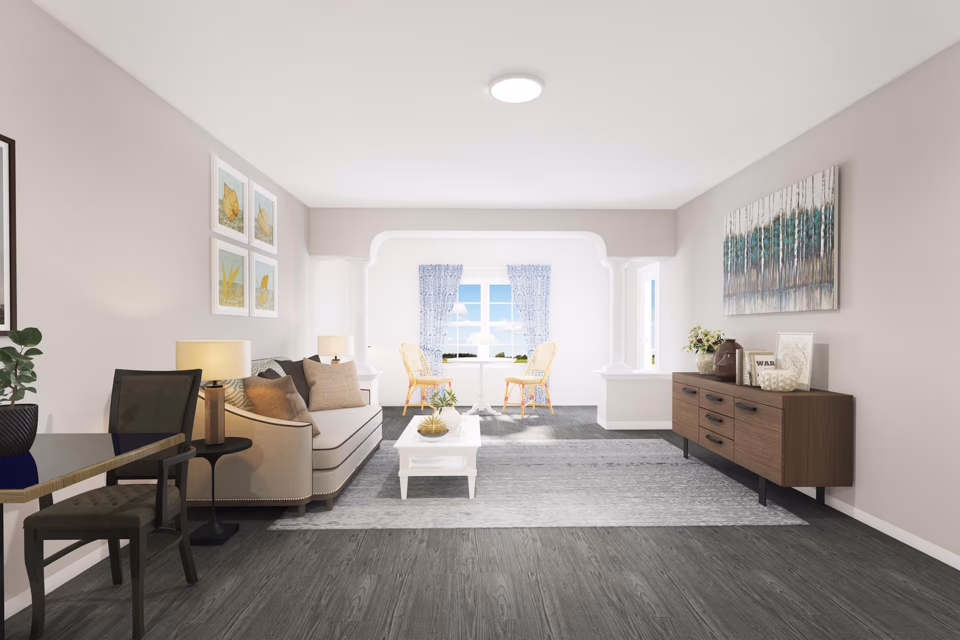 A bright and spacious living room with a beige sofa adorned with cushions, a white coffee table on a gray rug, two wicker chairs near a window with blue patterned curtains, a wooden sideboard with decorative items, and framed artwork on the walls.