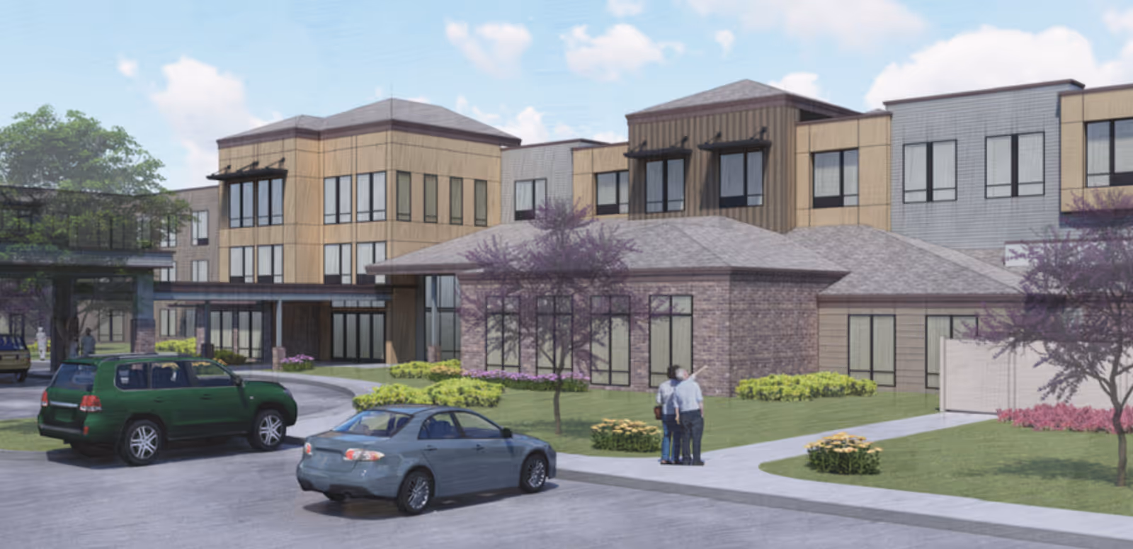 Exterior view of a modern three-story senior living facility with a circular driveway, landscaped garden with trees and flowers, and two cars parked near the entrance. Two people are standing on the sidewalk near the building.